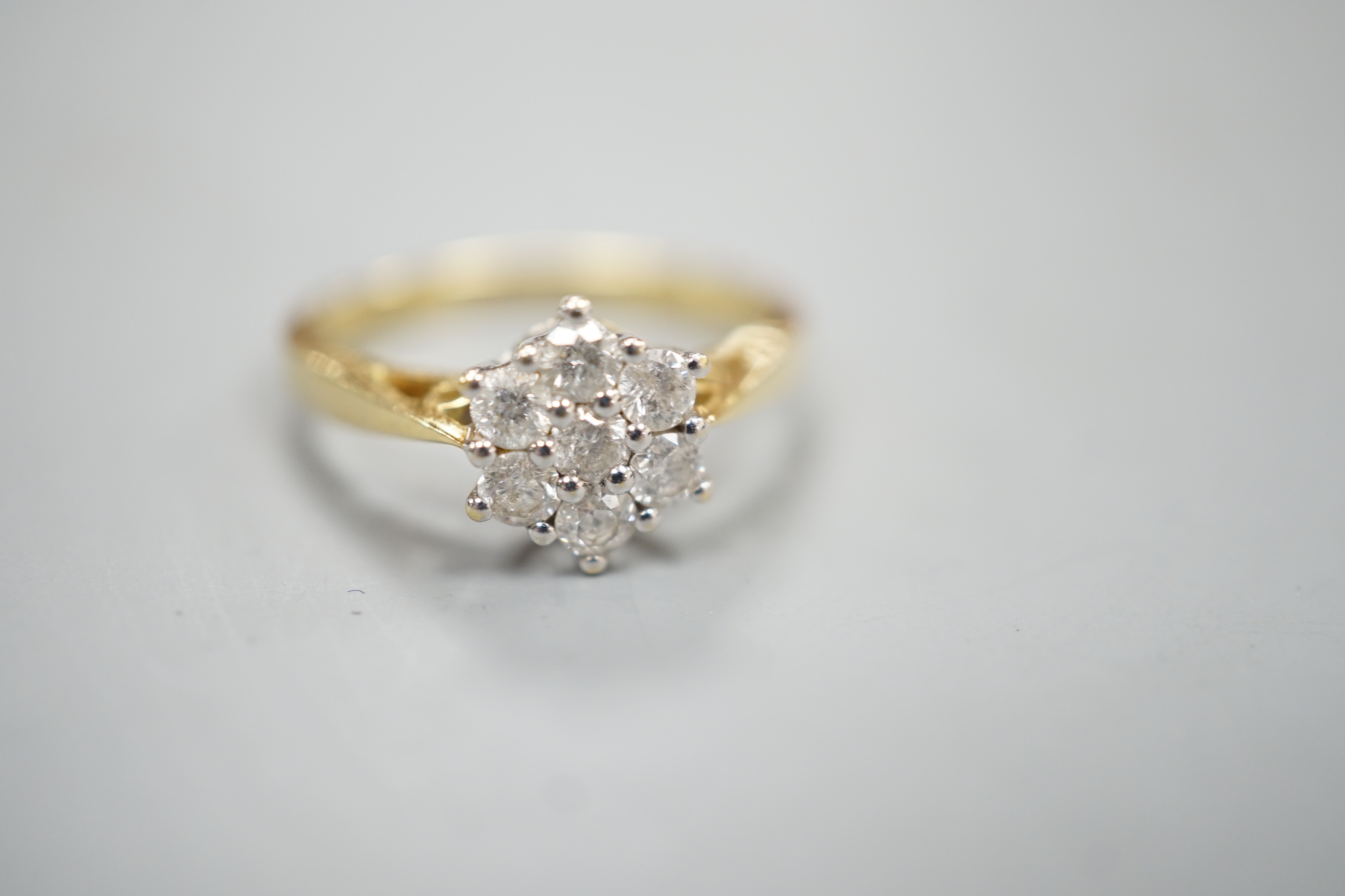 A modern 18ct gold and seven stone diamond set cluster ring, size O, gross 3.4 grams.